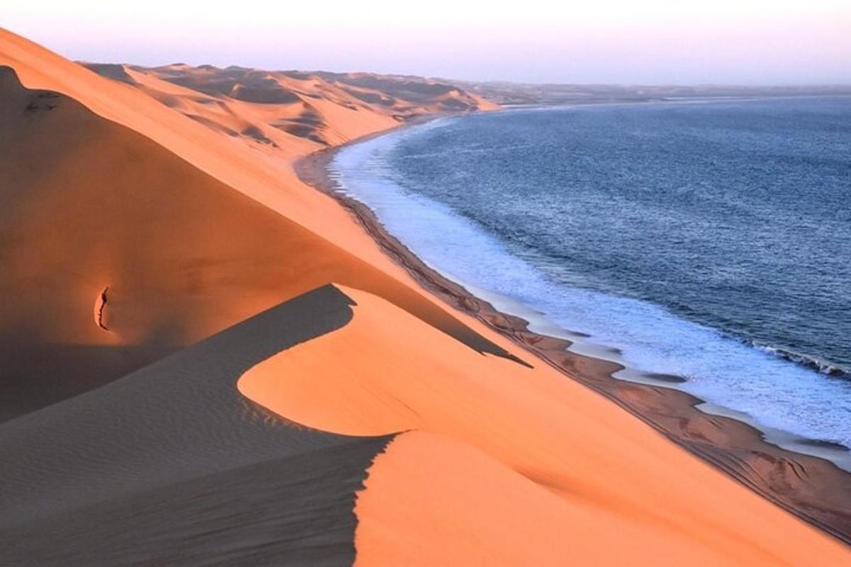 a person walking on a sand dune next to the ocean