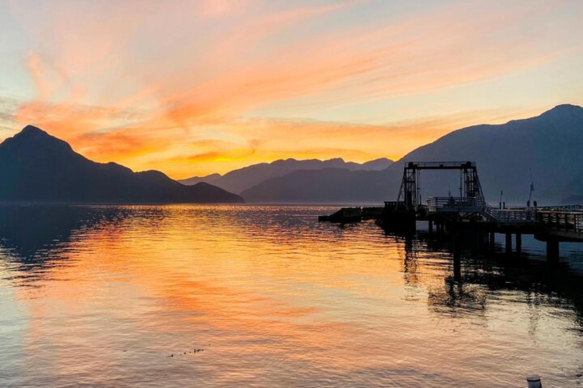 a sunset over a body of water with mountains