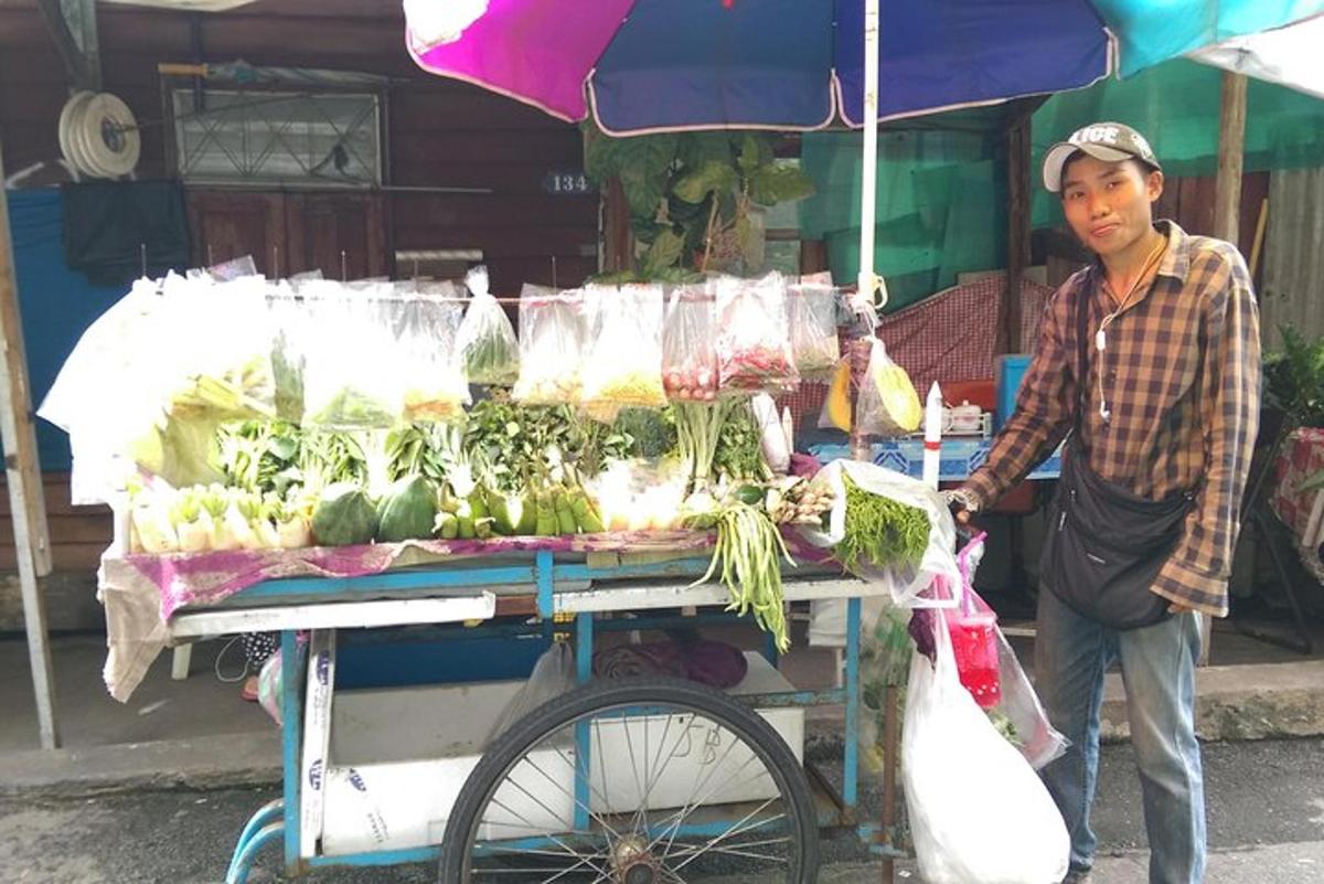 seorang lelaki berdiri di sebelah kereta dengan sayur-sayuran di atasnya