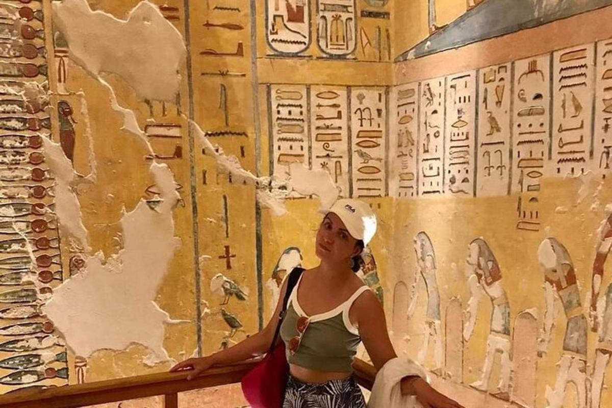 a woman standing in front of a wall with hieroglyphics