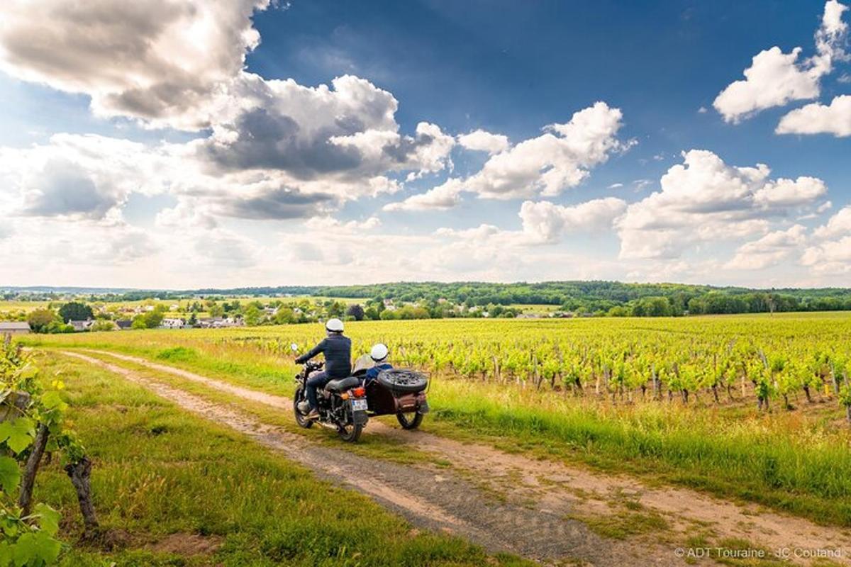 a man riding a motorcycle down a dirt road in a field