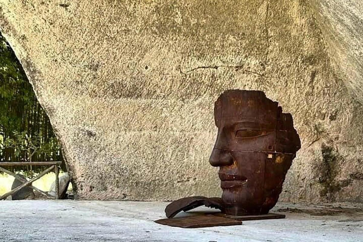 ένα άγαλμα ενός κεφαλιού που κάθεται δίπλα σε έναν τοίχο
