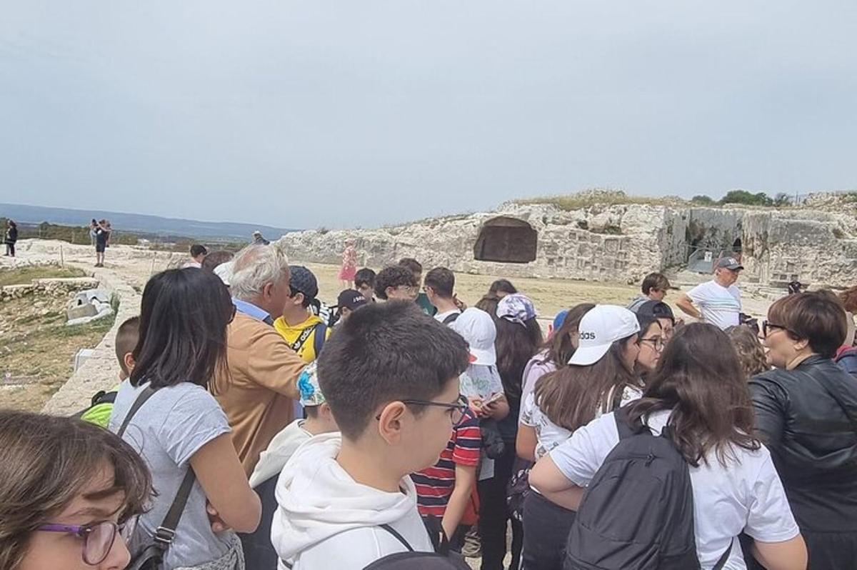 ένα πλήθος ανθρώπων που στέκεται μπροστά σε ένα ερείπιο