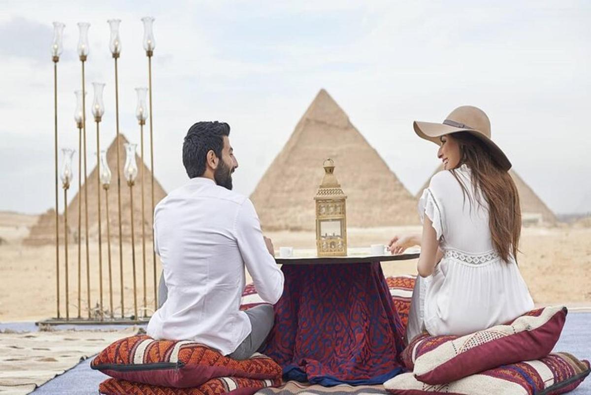 رجل وامرأة يجلسان على طاولة أمام الأهرامات