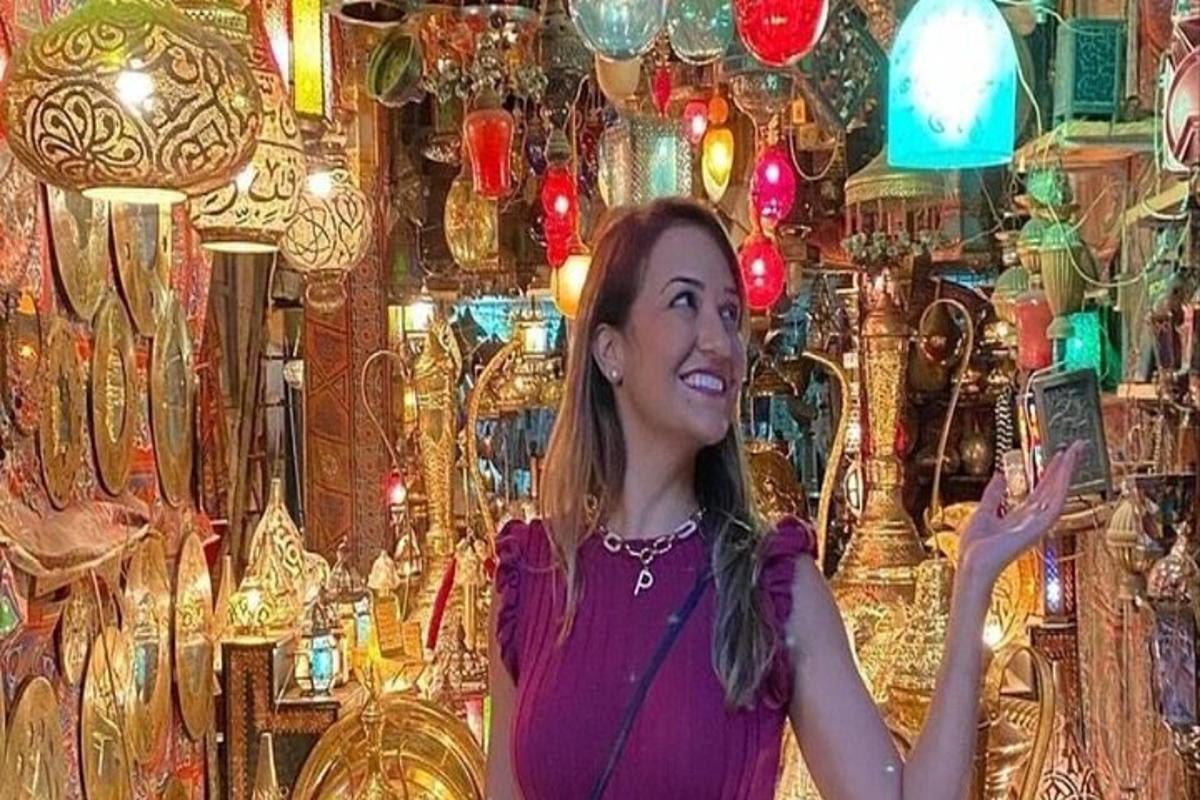 Una mujer sosteniendo un teléfono celular frente a una habitación con luces.
