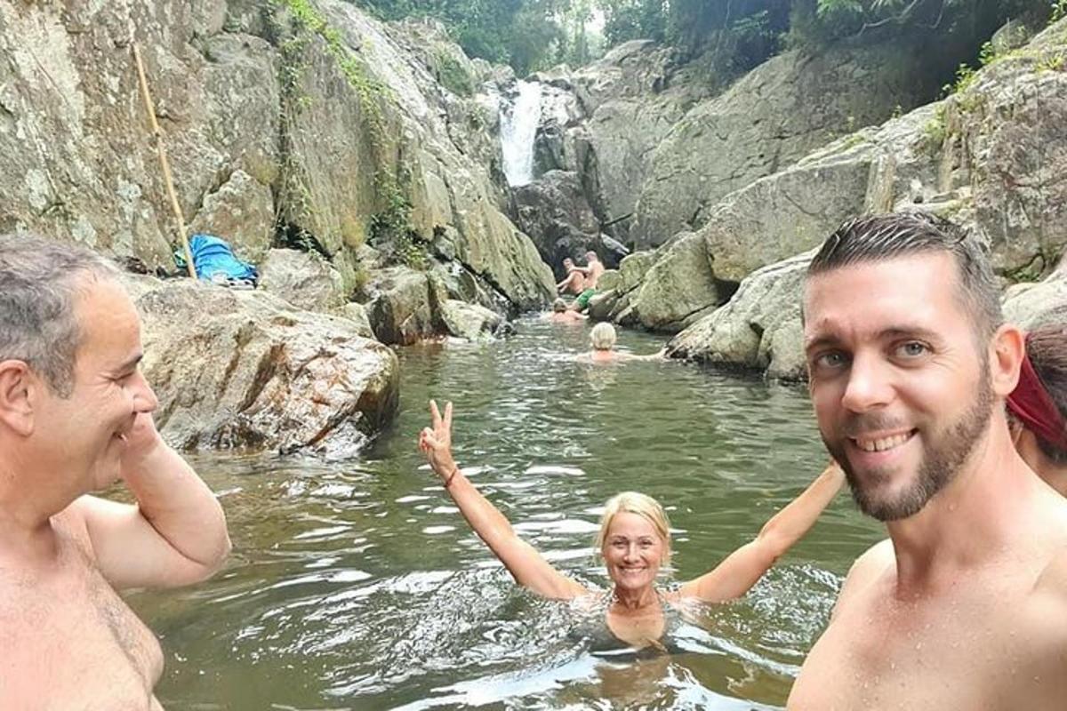 a group of people in the water near a waterfall