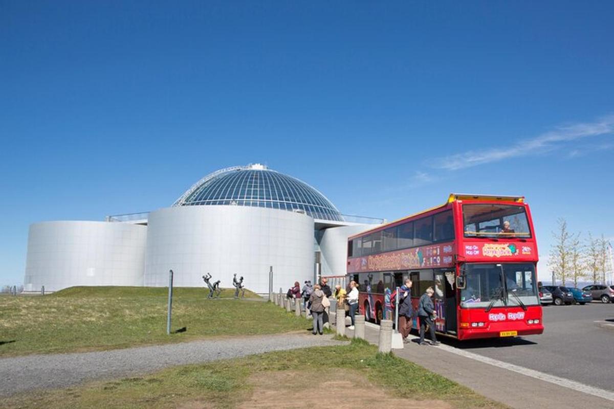 červený dvoupatrový autobus projíždějící kolem budovy