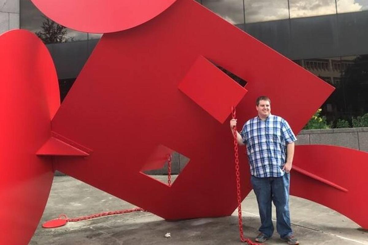a man standing next to a large red sculpture