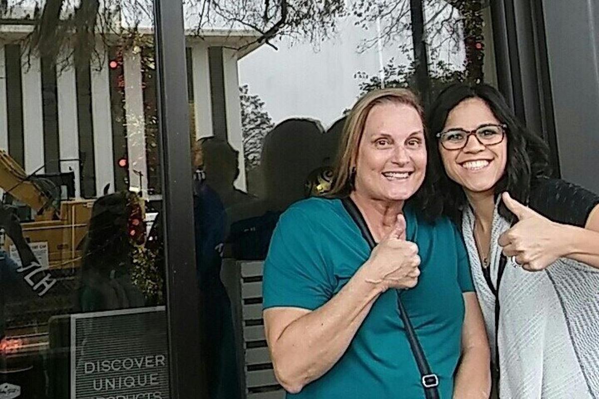 two women giving the thumbs up in front of a window