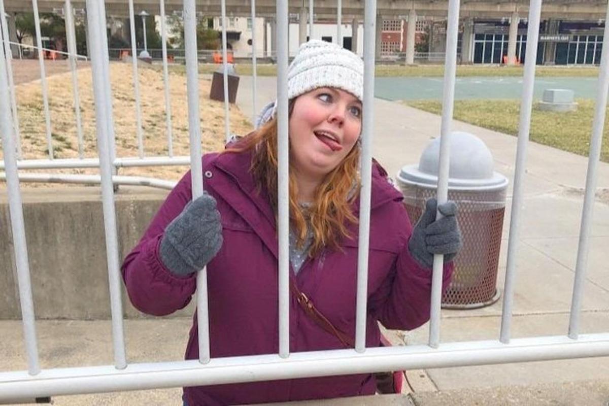 a woman is standing behind a gate
