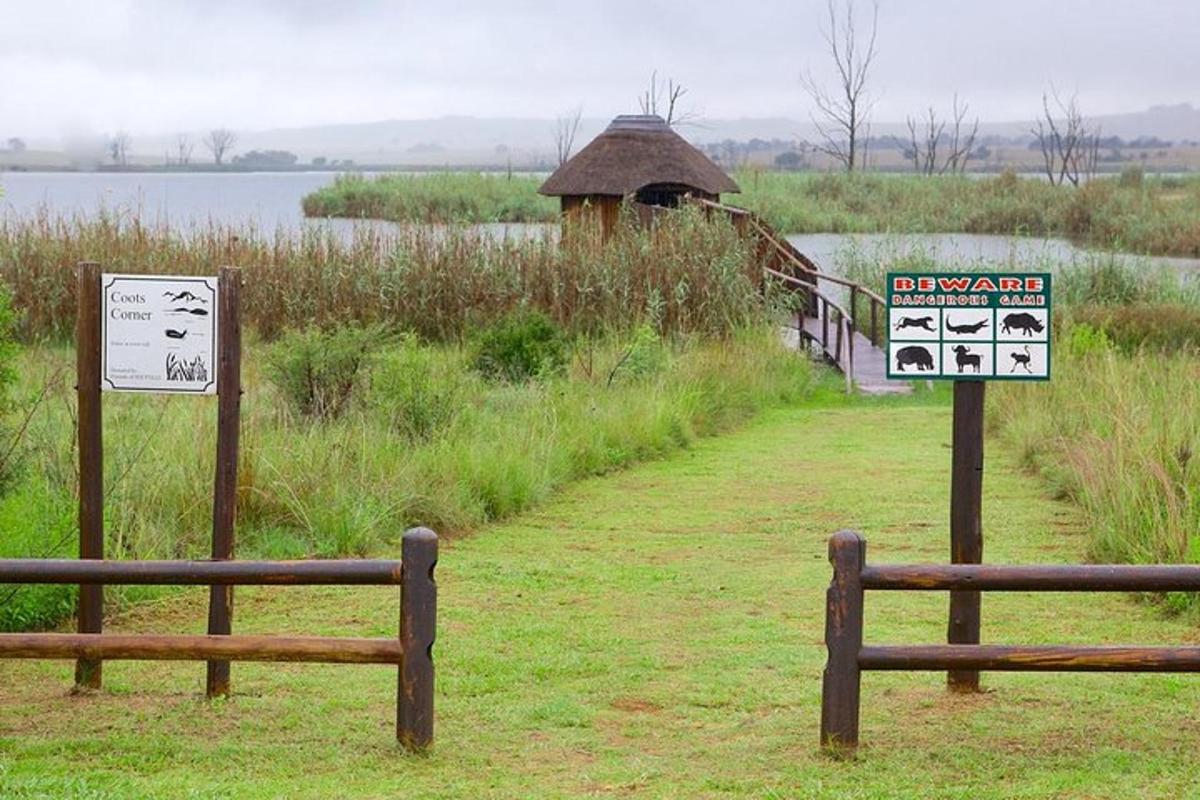 two signs in front of a field with a building