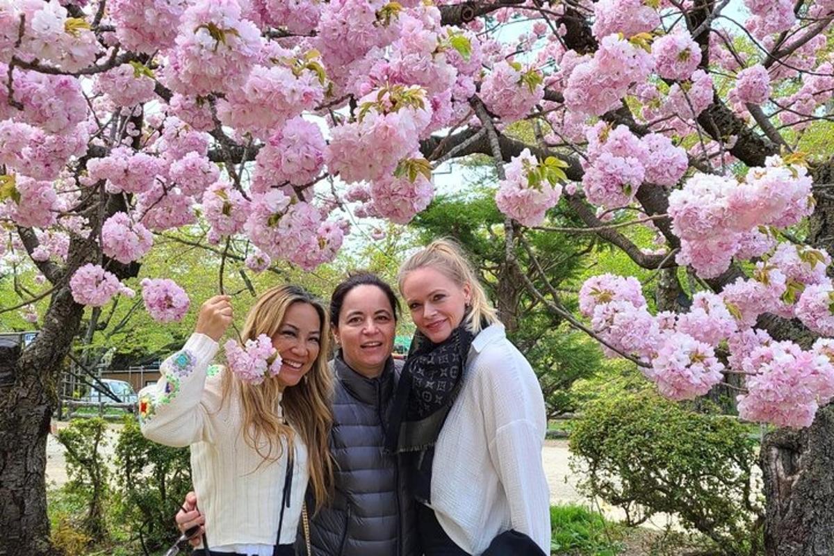 three women standing in front of a tree with pink flowers
