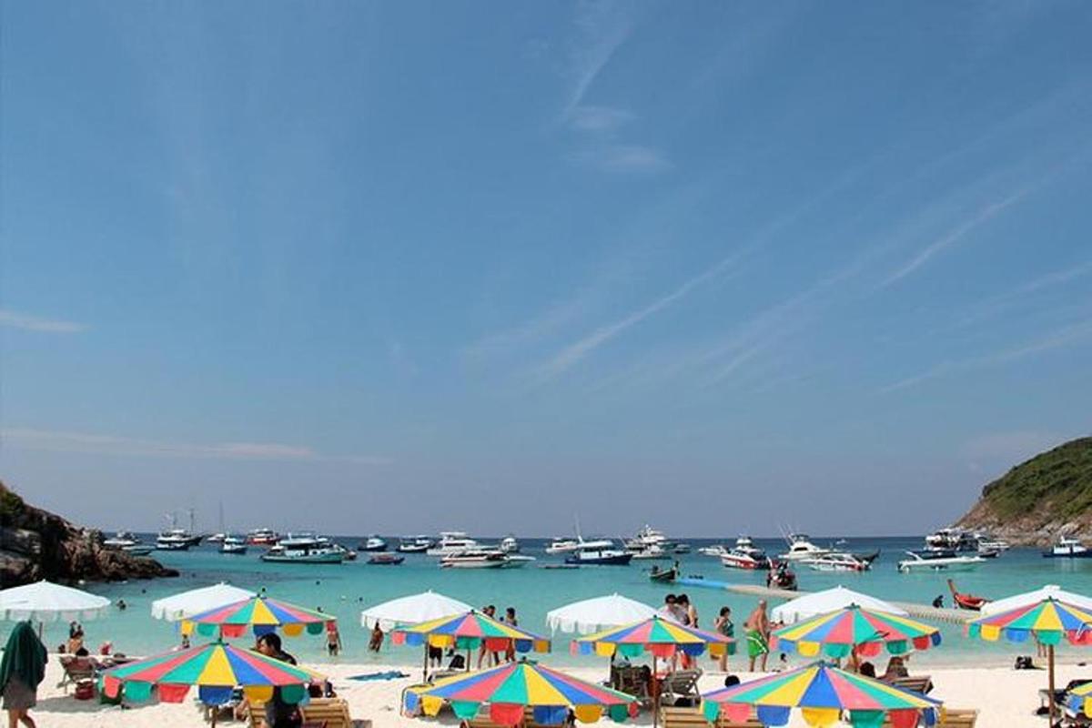 emberek a strandon, napernyőkkel és csónakokkal a vízben