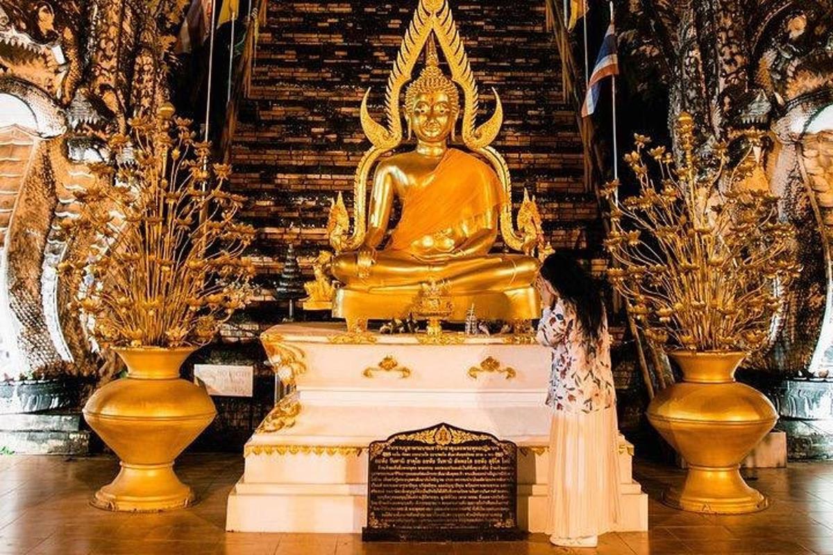 Una mujer parada frente a una gran estatua de oro