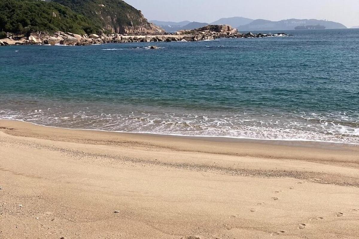 una platja de sorra amb l'oceà i les muntanyes al fons