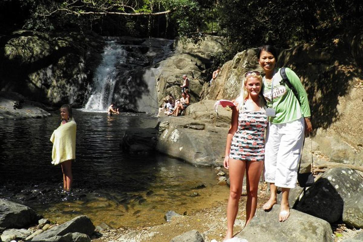 a woman and a girl standing in front of a waterfall