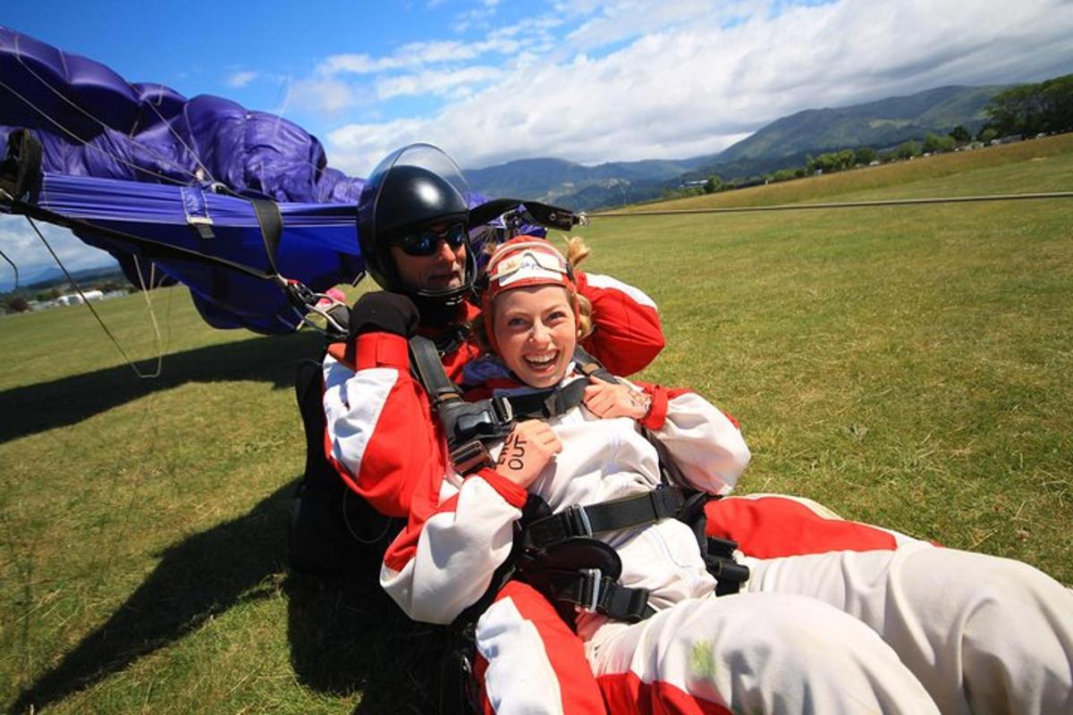 a man and a woman laying on the grass with a parachute