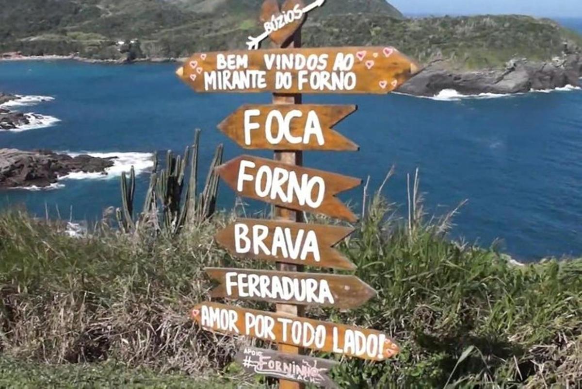 a group of signs on a hill near the ocean