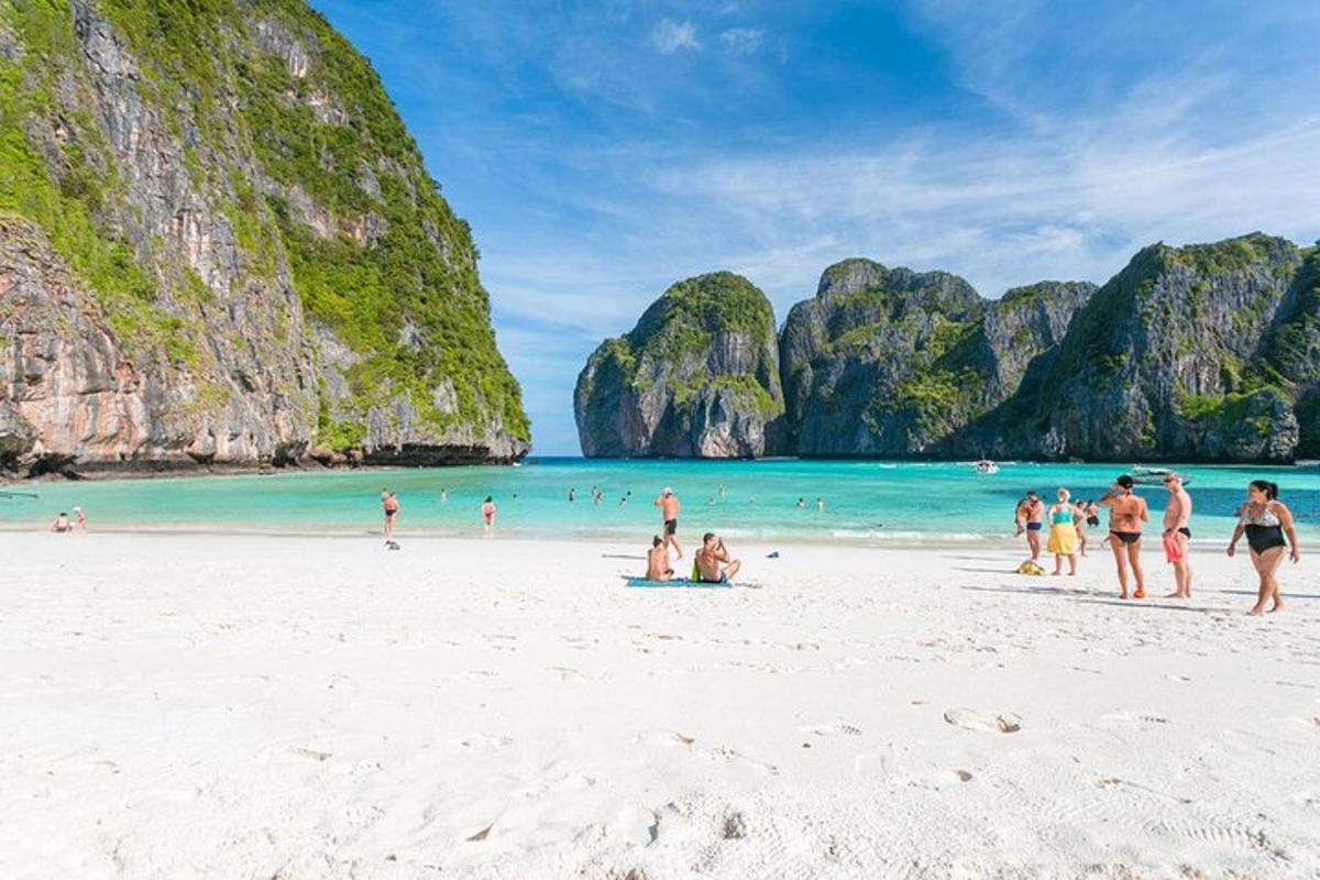 sekumpulan manusia di pantai dengan tebing batu kapur