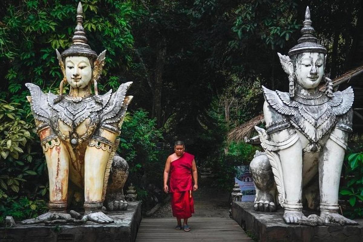 ein Mann in einem roten Kleid, der zwischen zwei Statuen geht