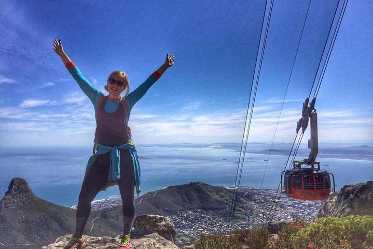 žena stojící na vrcholu hory se vztyčenýma rukama