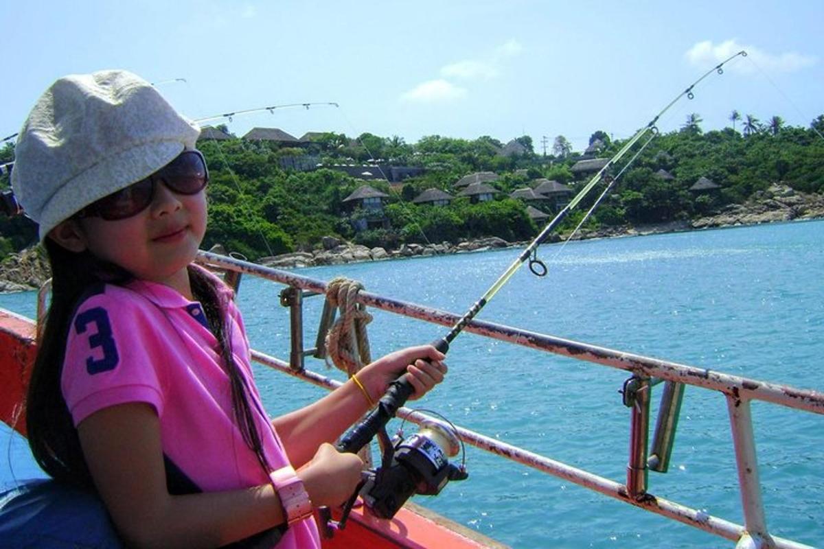 seorang gadis kecil memegang pancing di atas perahu