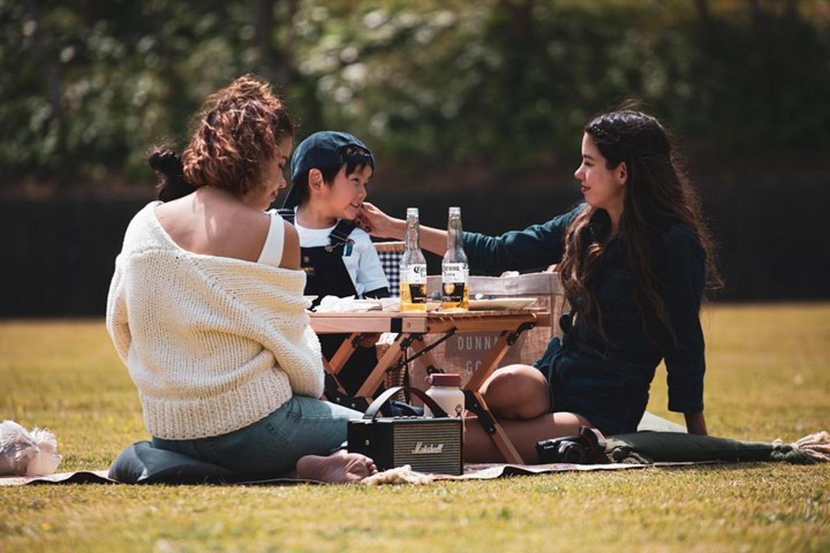 three women sitting at a picnic table in a field
