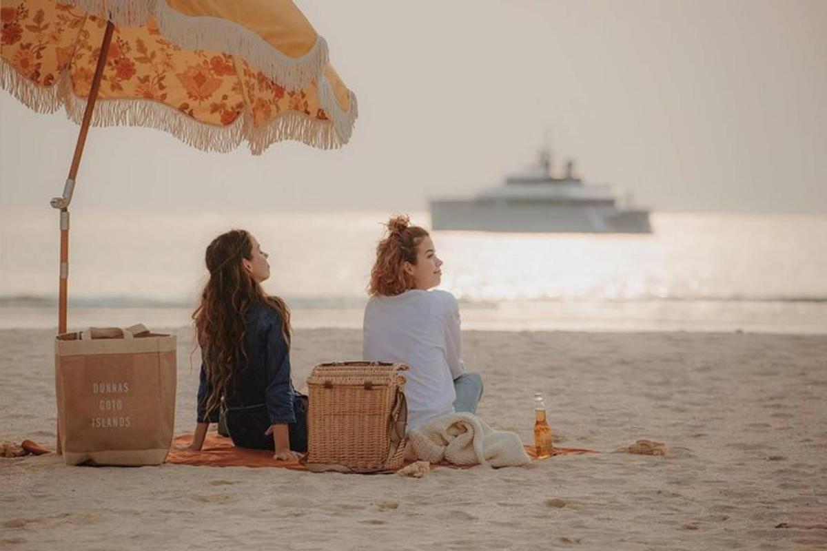 due donne sedute sulla spiaggia sotto un ombrellone