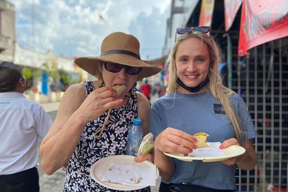 duas mulheres comendo comida em pratos na rua
