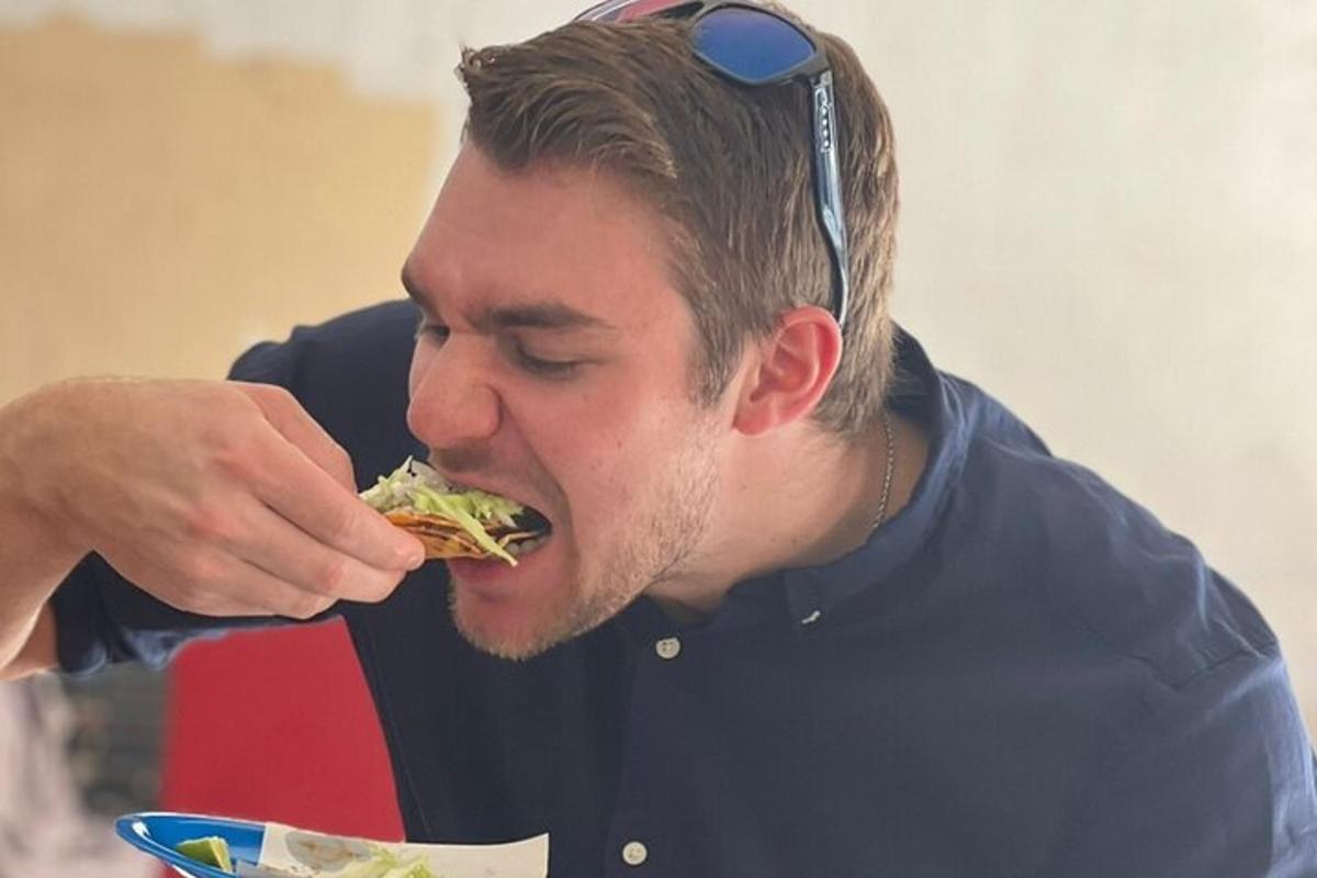 en mand med solbriller på hovedet spiser en sandwich