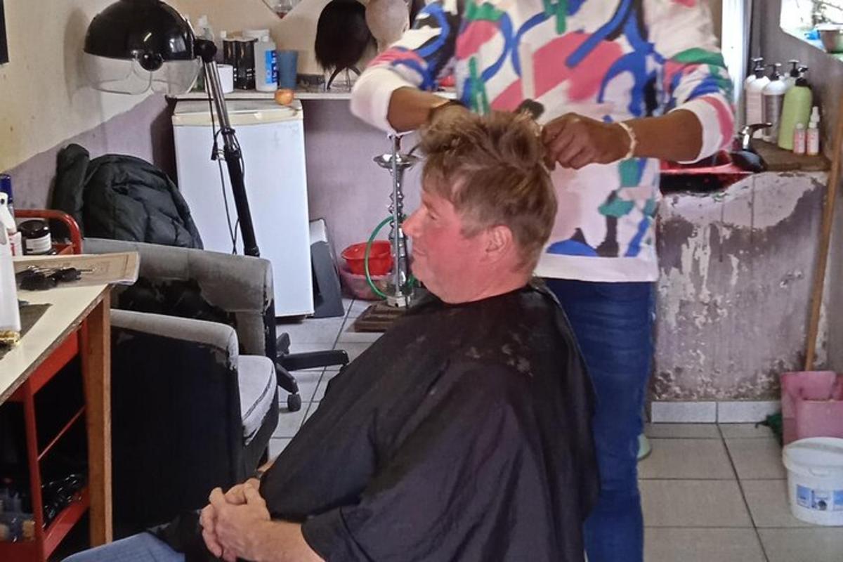 a woman cutting a mans hair in a barber shop