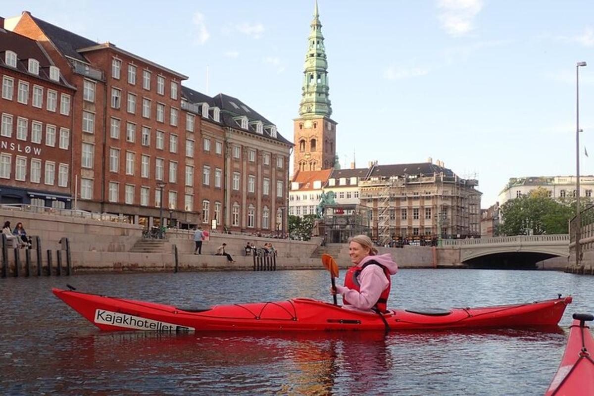 kona í rauðum kajak á á í borg