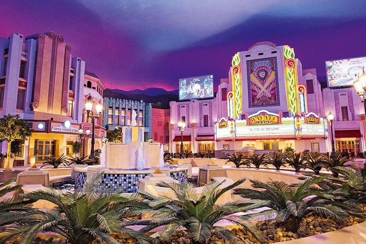 a shopping center with palm trees and buildings at night