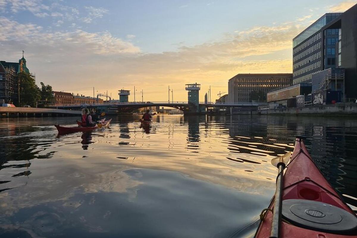 two people in kayaks on a river with a bridge
