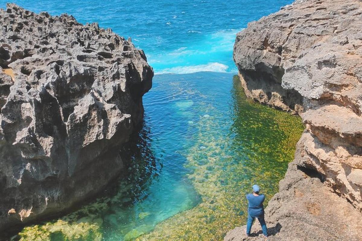 ein Mann, der auf einer Klippe steht und auf das Wasser blickt