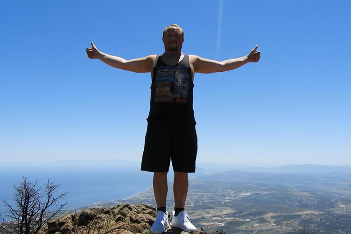 un home dret al cim d'una muntanya amb els braços estesos