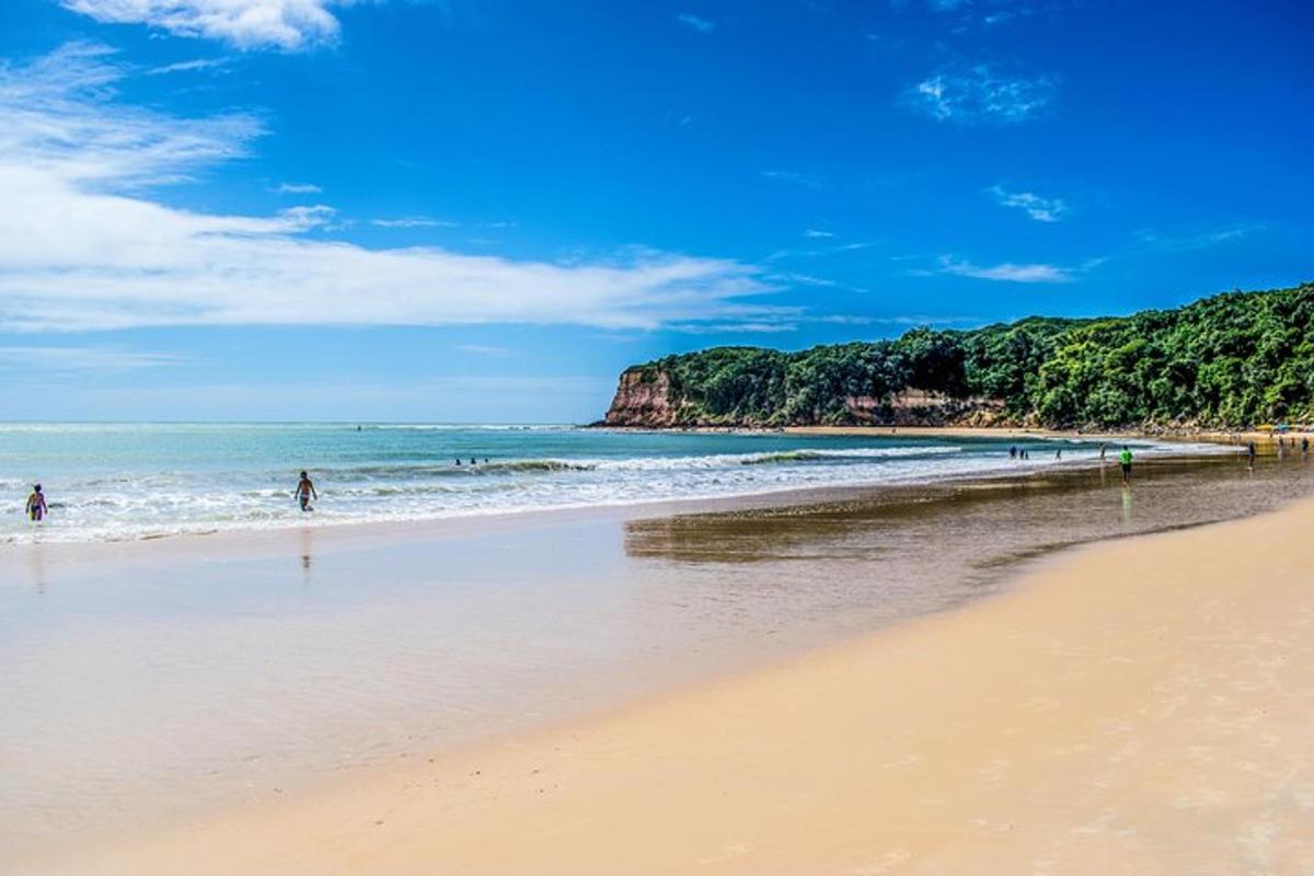 a beach with people walking in the ocean
