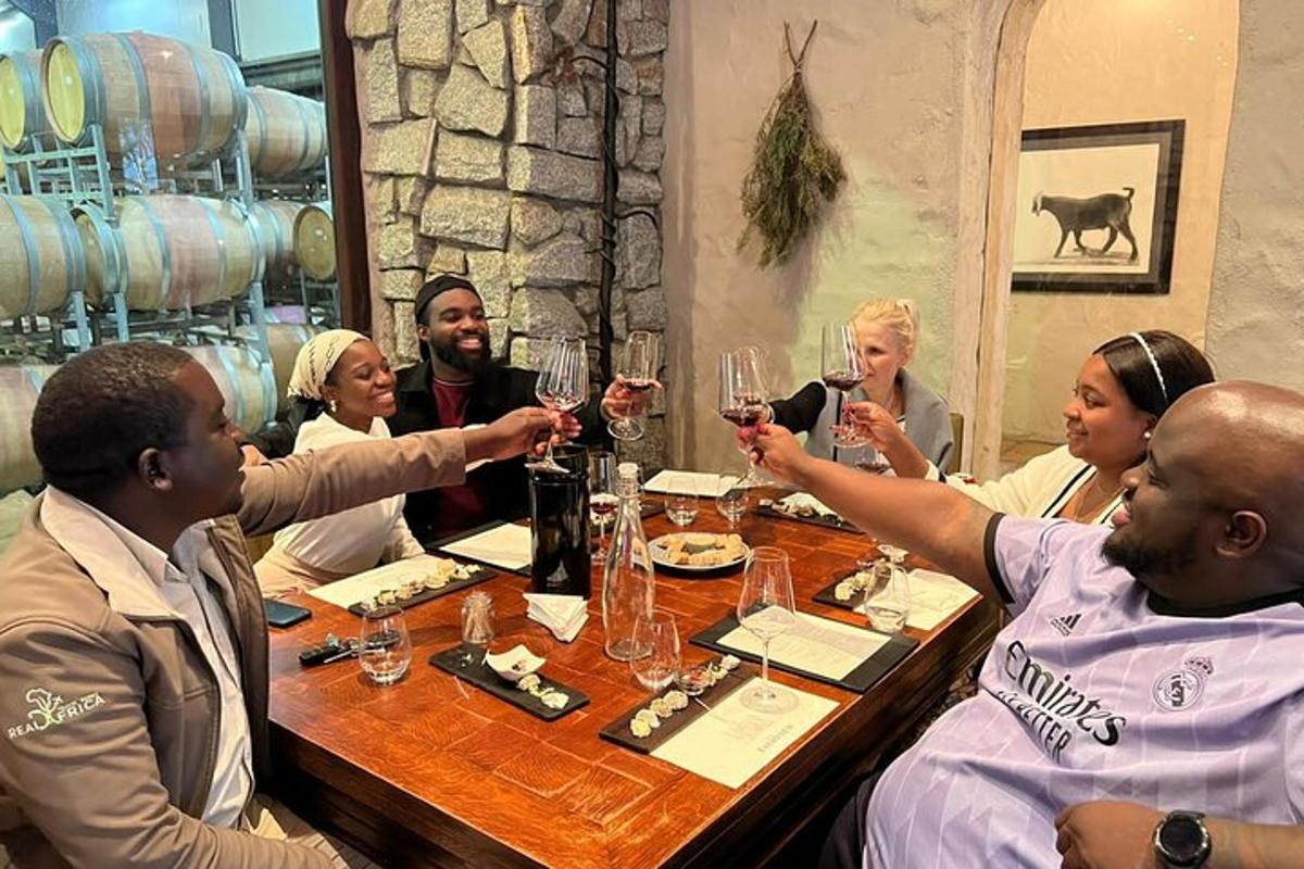 skupina ljudi, ki sedijo okoli mize in pijejo vino