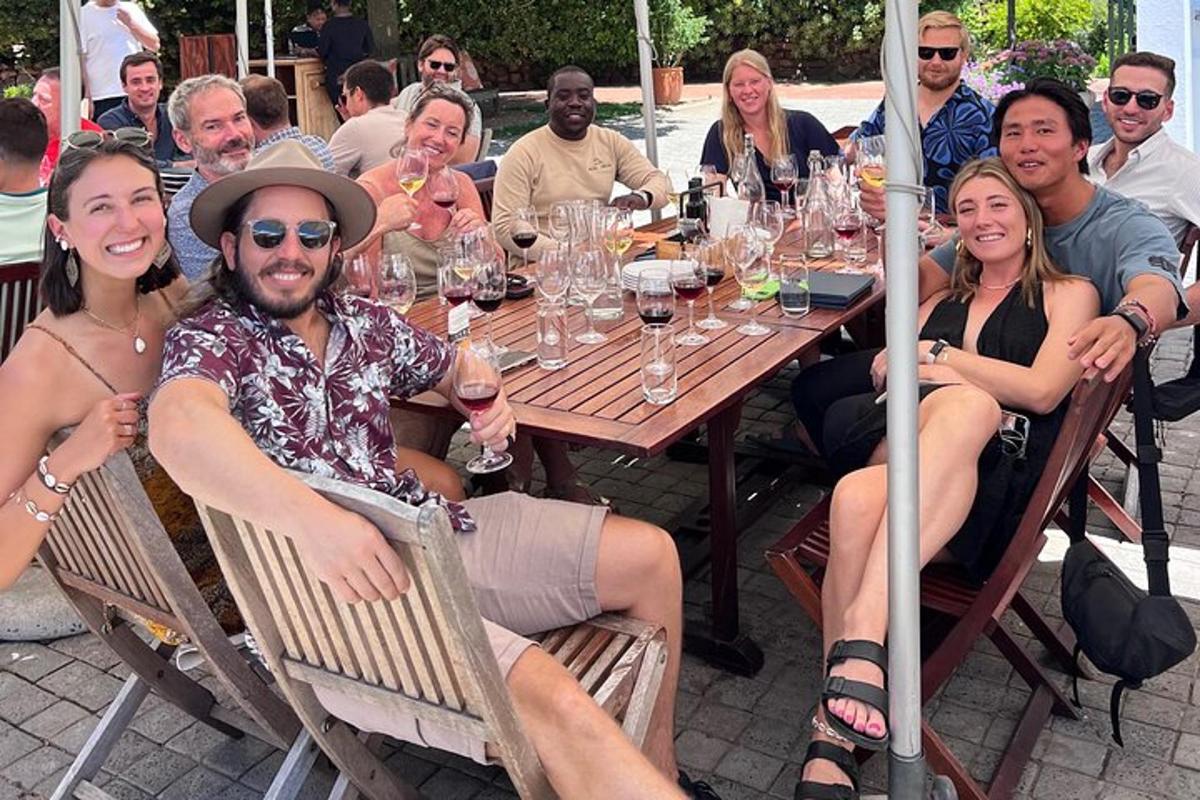 eine Gruppe von Menschen sitzt mit Weingläsern um einen Tisch