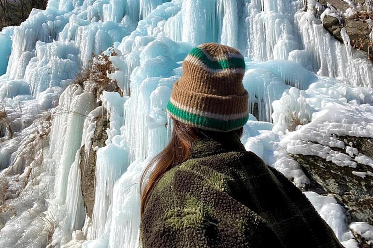 a woman is looking at a frozen waterfall