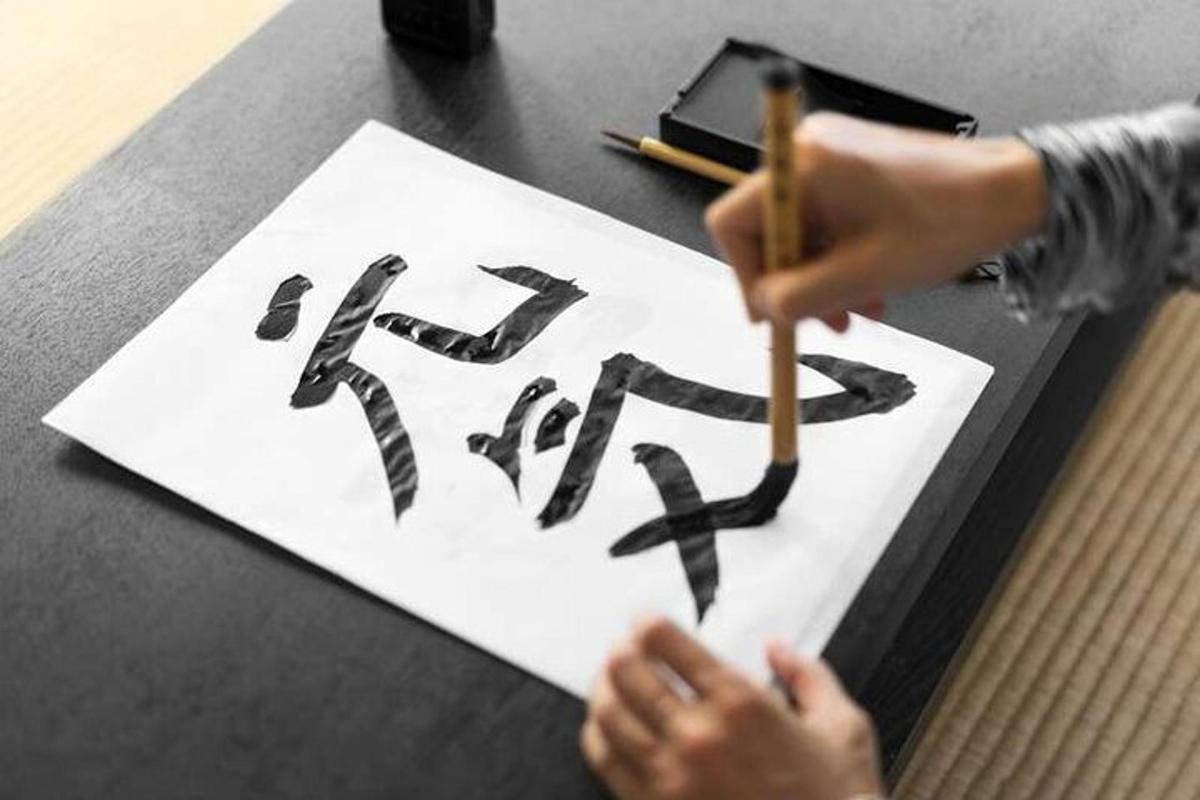 a child holding a pencil and writing a kanji on a paper