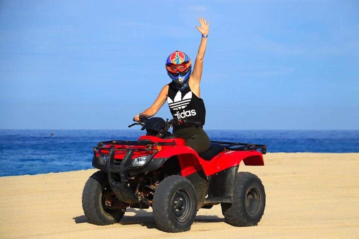 una persona conduciendo un quad por la playa