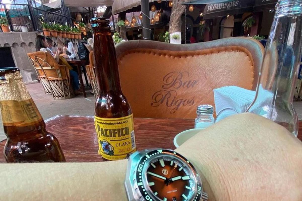 Una botella de cerveza y un reloj sobre una mesa