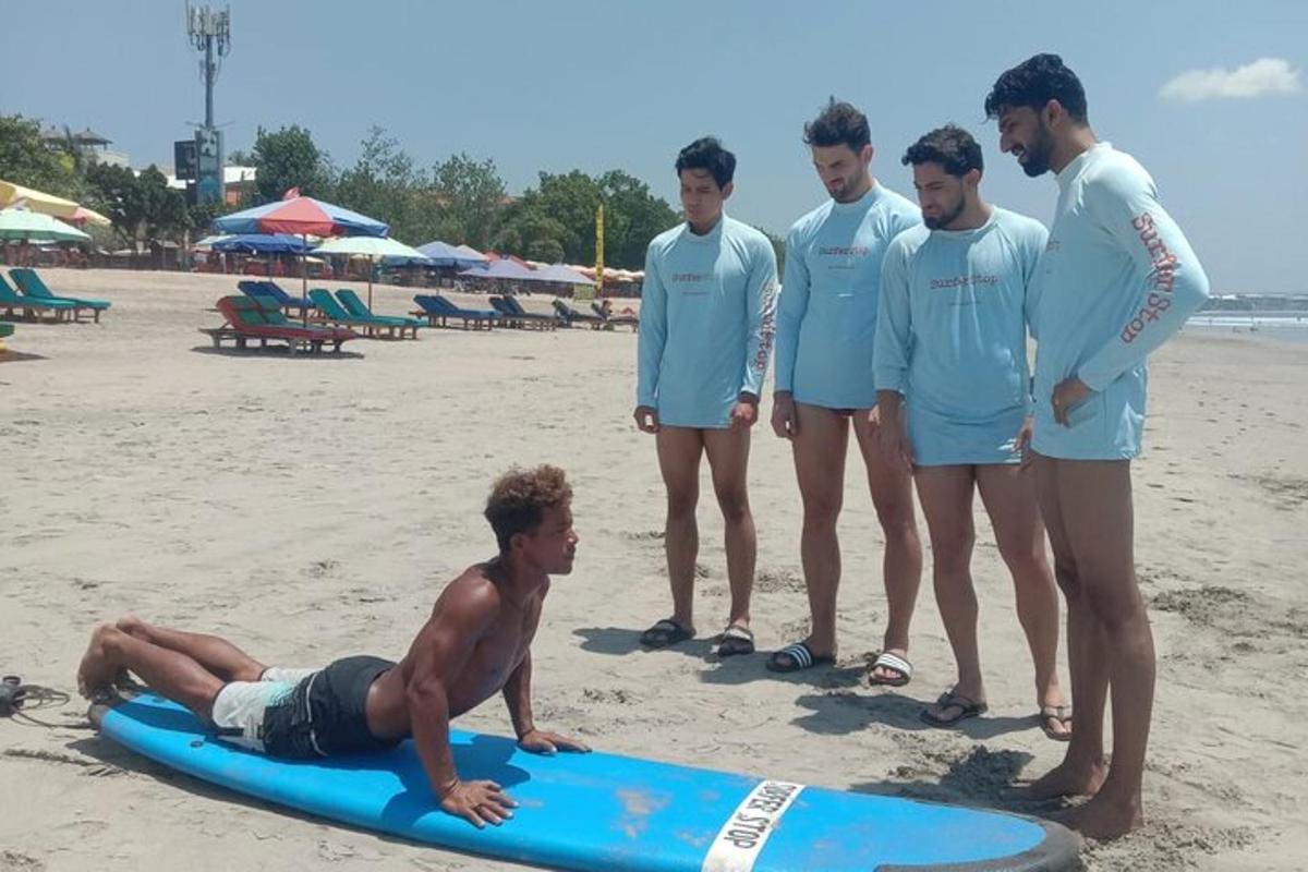 a group of men standing on a surfboard on the beach