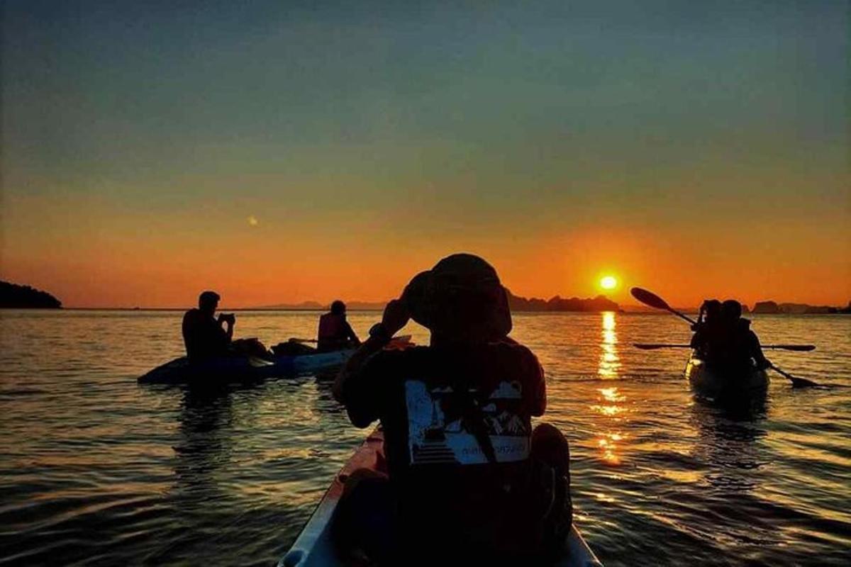 a group of people kayaking on the water at sunset