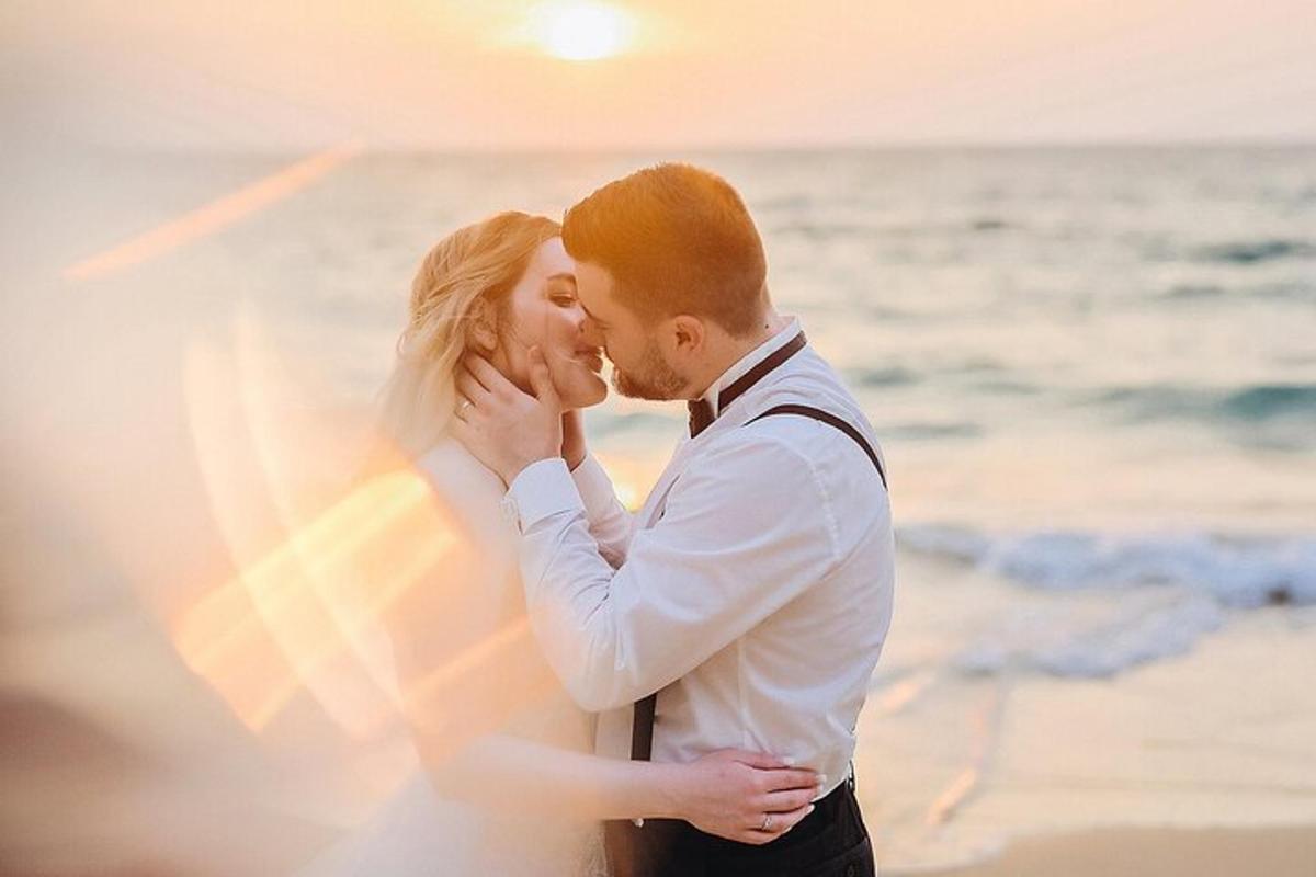 a bride and groom kissing on the beach