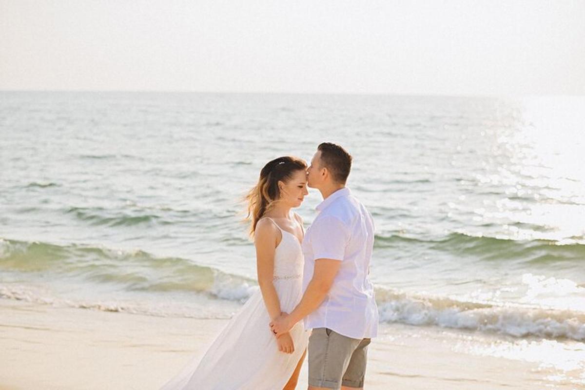 a bride and groom standing on the beach