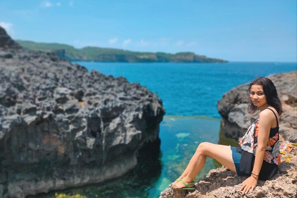 a woman sitting on a rock by the water