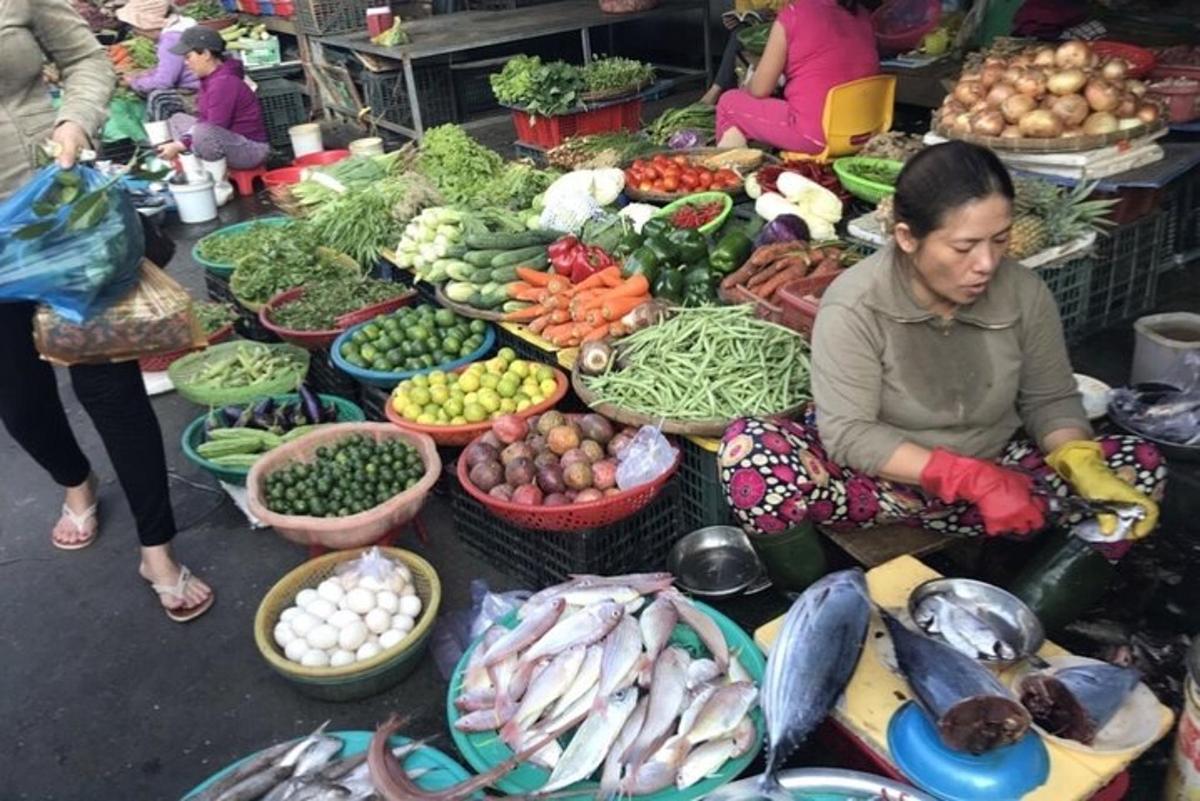 una donna seduta davanti a un mercato pieno di verdure