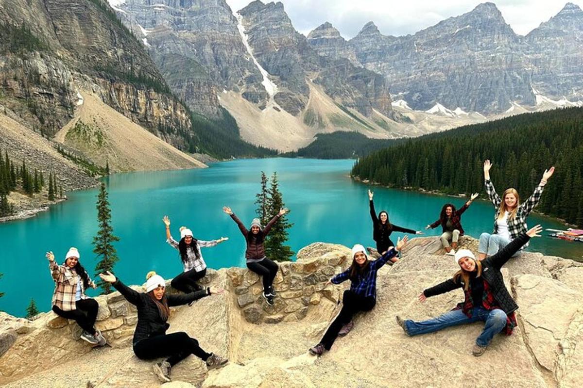 a group of people sitting on a rock in front of a lake